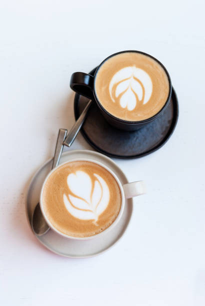 istock Black and white coffee cups with drawings on a white background (top view) 1442618698
