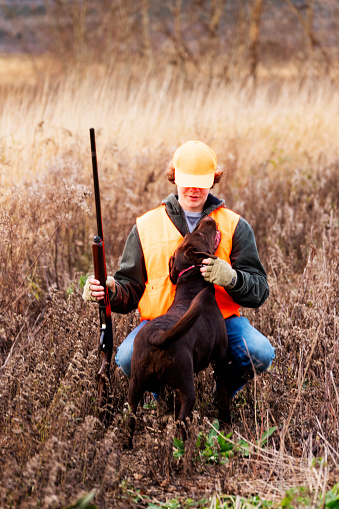 A teen hunter with his Labrador Retriever hunting dog on a pheasant hunt in the autumn