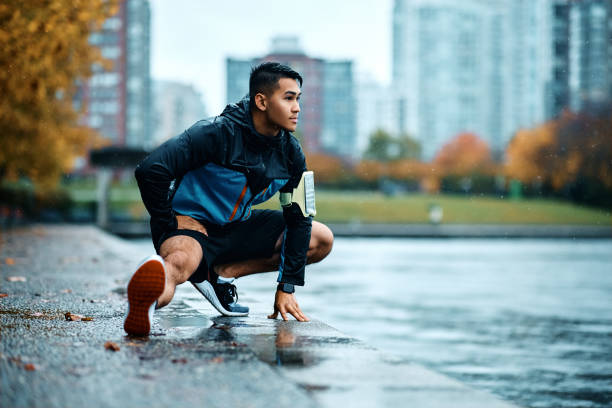 istock Athletic man stretching his leg while exercising outdoors on rainy day. 1442635524