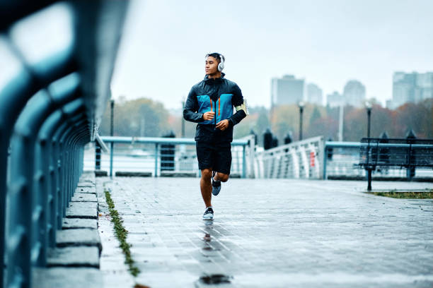 istock Young athletic man jogging while exercising outdoors in the rain. 1442635704