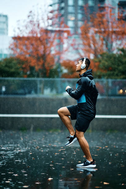 istock Motivated athlete running on the spot while warming up outdoors in the rain. 1442636072