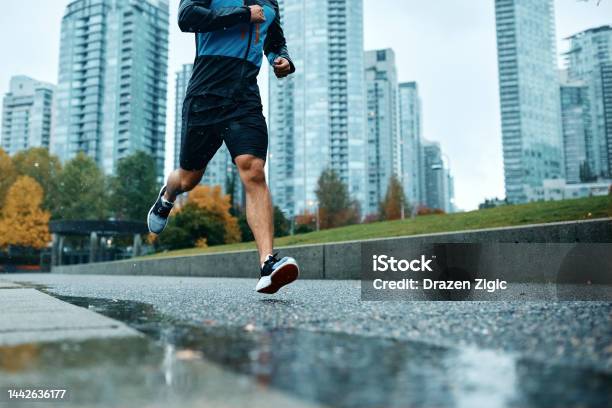 Unrecognizable Athletic Man Running During Rainy Day Stock Photo - Download Image Now