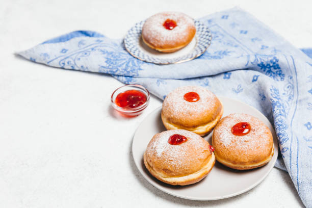 Sufganiyot jelly doughnuts cooked in oil on white table background. Traditional Jewish festive food dessert for Hanukkah holiday. Flat lay, top view. stock photo