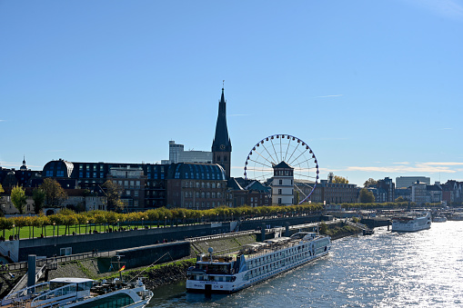 Düsseldorf, November 13, 2022 - The Rhine promenade in Düsseldorf with Ferris wheel, castle tower and St. Lambertus Basilica seen from Oberkassel Bridge.