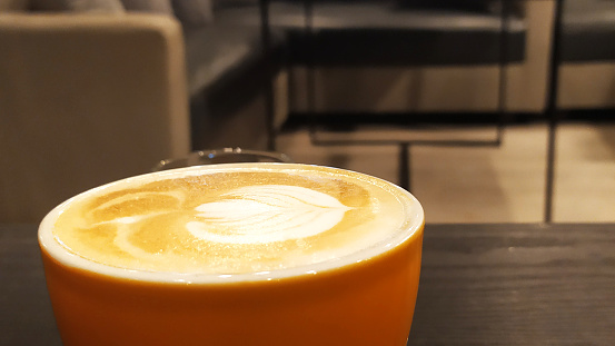 the orange cup contains a caffe latte, which is coffee and fresh milk