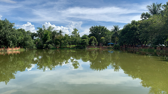 A view of a lake with trees, and a blue cloudy sky