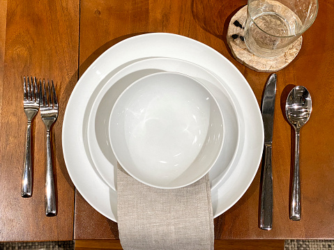 White-on-white place setting with contemporary square plates; empty copy space on top plate.