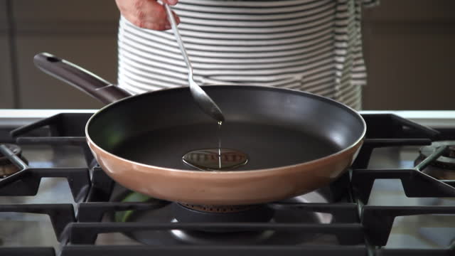 pouring olive oil into a frying pan