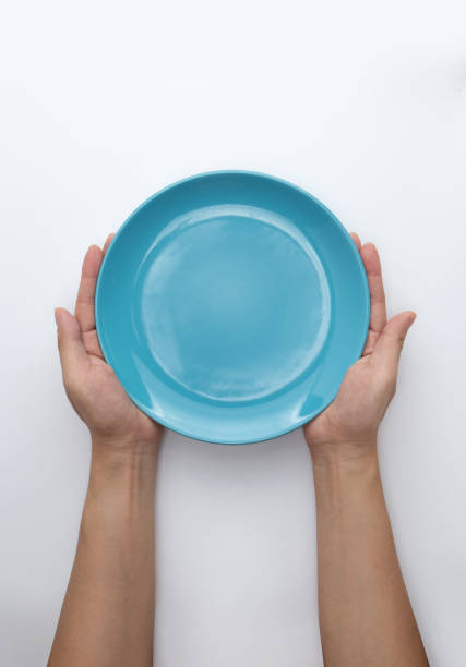 istock Male hands are holding a blue plate on a white isolated background 1442667408