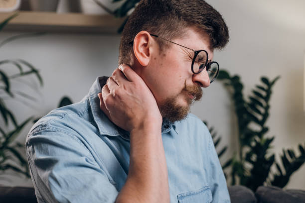 istock Young bearded man in eyeglasses studying until night at computer with neck pain. Close up of tired worker kneading neck, muscle recovery and massage. Neck pain, cervical osteochondrosis concept 1442673006