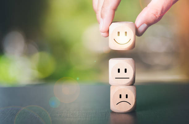 istock Human hand picking a wooden block with a smiley icon, 1442673589