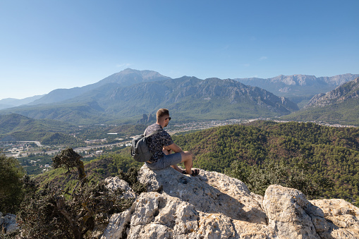 The man on a mountaintop admiring the surrounding mountain landscape in the summertime