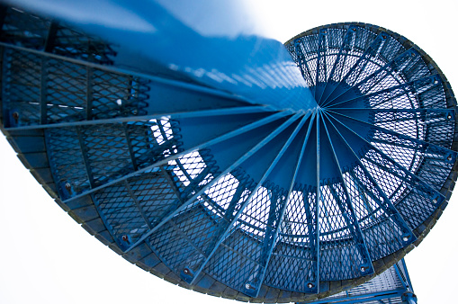 A top view of a blue spiral staircase on a white background.