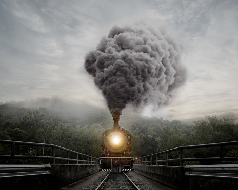 The front of a moving train blowing smoke