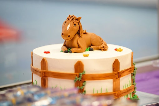 A decorative birthday cake with a horse topper on a table