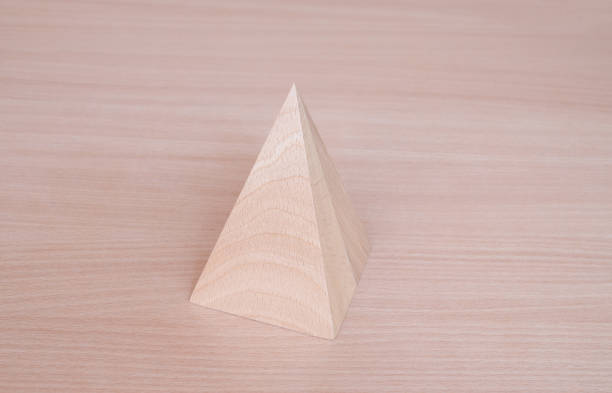 istock Wooden pyramid geometric model shape on wood table background. Perfect geometry bodies concept 1442684717