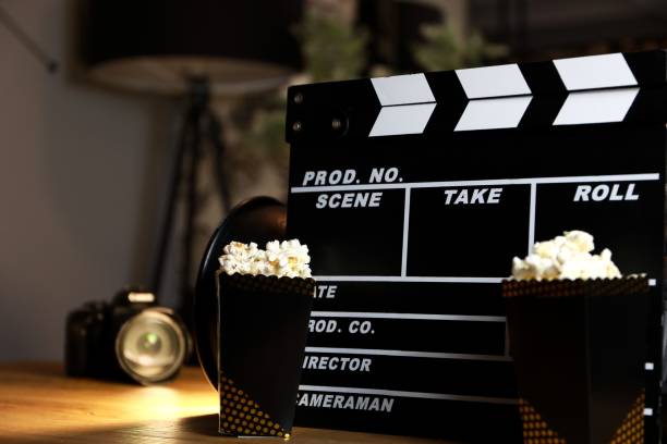 istock Closeup of a lovely clapperboard with popcorn buckets placed on a table at night 1442685323