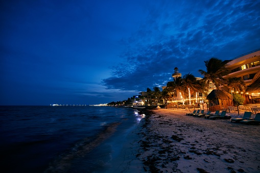 Night illumination of coast, night bars, cafes, sun beds on the beach of Playa del Carmen Quintana Roo Mexico.Beautiful night seascape, dark blue sky