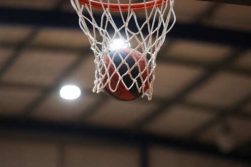 A basketball lands in a basketball net