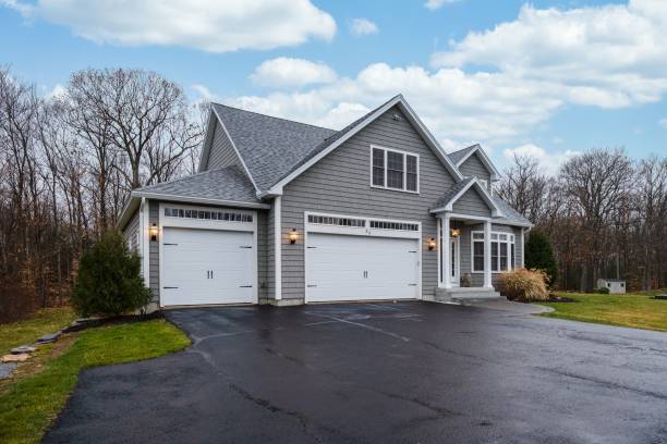 Gray-walled suburban house with white asphalt driveway A gray-walled suburban house with white asphalt driveway driveway stock pictures, royalty-free photos & images