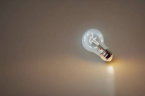 istock Closeup shot of an illuminated lightbulb on a gray background 1442692762