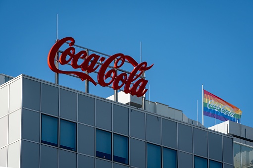 Rotterdam, Netherlands – June 11, 2022: The Coca Cola logo with LGBT flag at The Coca-Cola Company office building in Rotterdam
