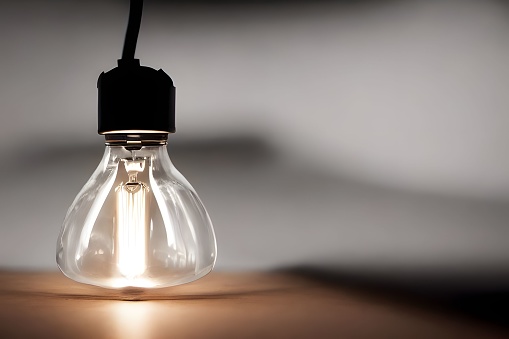 A closeup shot of an illuminated lightbulb on a gray background