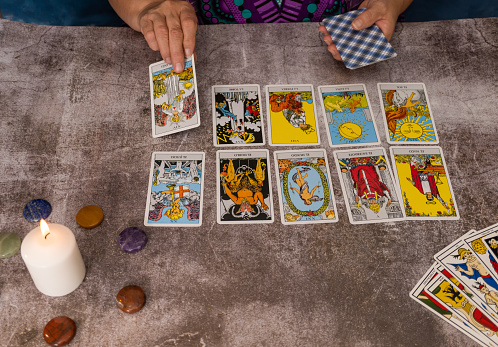 older white-haired woman reading tarot cards on a wooden table with candle