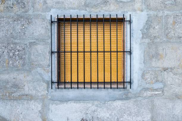 istock Window with the shutter down and iron bars on a concrete wall, security concept 1442693886