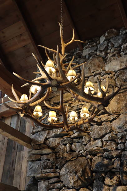 Deer antler chandelier in front of a rock wall at a lodge A deer antler chandelier in front of a rock wall at a lodge antler chandelier stock pictures, royalty-free photos & images