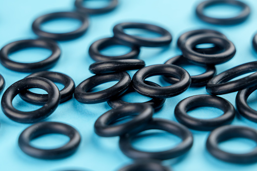 Black sealing rubber gaskets on colored blue background. Hydraulic spare parts. Macro