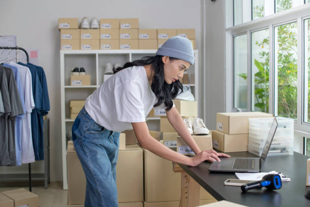 istock Asian e-commerce female business owner working on laptop computer in store warehouse. 1442702557