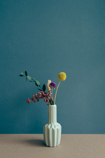 Vase of dry flower on table. navy blue wall background. home interior