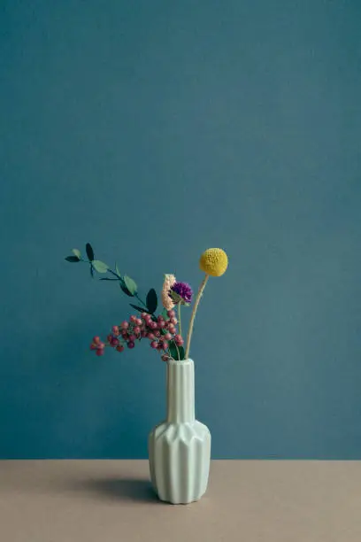 Photo of Vase of dry flower on table. navy blue wall background. home interior