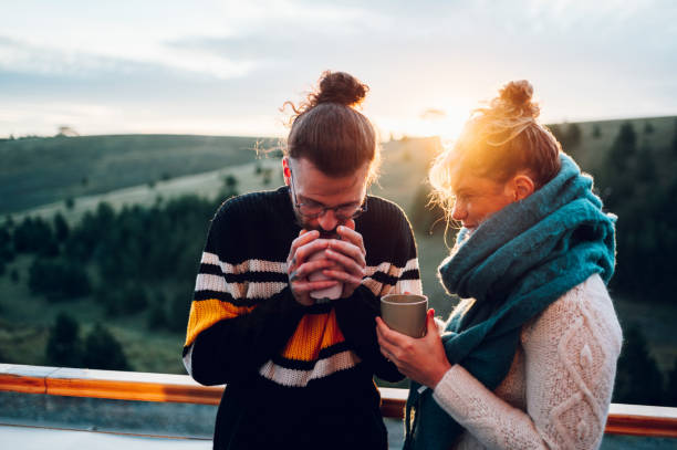 istock Young couple drinking coffee or tea while standing on their balcony at sunrise 1442706010