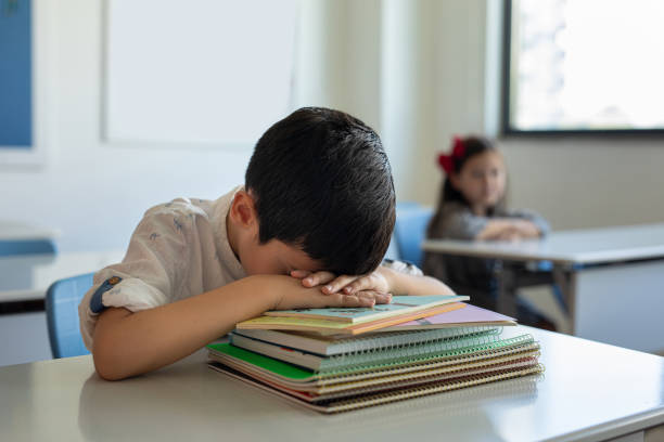 Young boy sleeping at her desk in a classroom stock photo