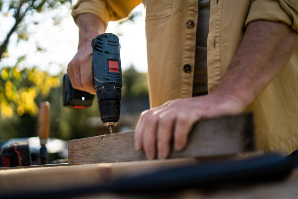 Close-up of handyman carpenter working in carpentry diy workshop outdoors with drill. stock photo