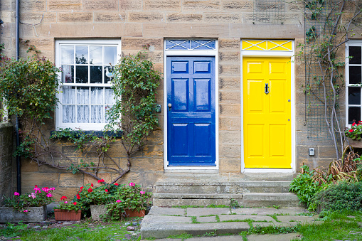 Blue and yellow painted front doors on terraced houses. Holiday cottages, Robin Hoods Bay, Yorkshire, UK