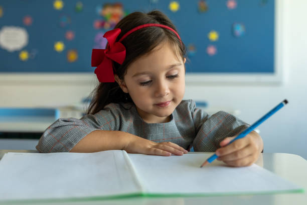 istock Schoolgirl sits writing or drawing on textbook in classroom 1442711640
