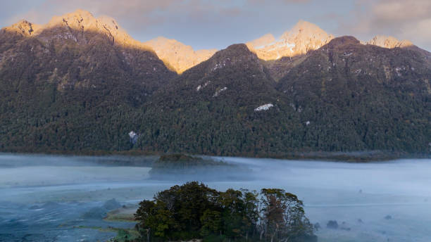 a vista da montanha da cena do outono e nebulosa pela manhã com a cena do céu do nascer do sol no parque nacional fiordland - new zealand forest landscape mountain - fotografias e filmes do acervo