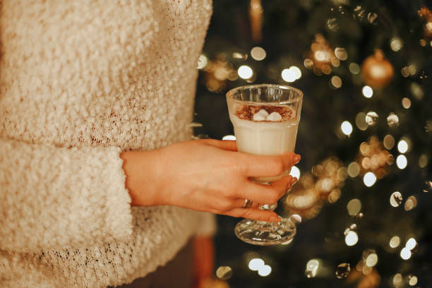 istock Woman drinking homemade eggnog decorated with marshmallows while sitting near xmas tree 1442718948