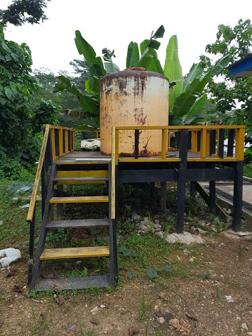 yellow water reservoir used to collect rainwater, yellow with a fence around it made of black and yellow wood, located at a coal mine site