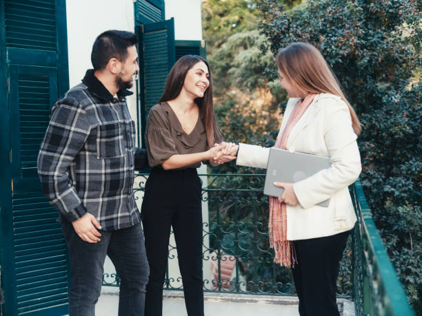 agente imobiliário com um jovem casal em uma nova casa - mansion real people candid meeting - fotografias e filmes do acervo