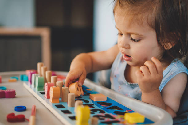 Baby girl playing with different color wooden elements making tasks for education and brain exercise. Counting math play game. Wooden toys.