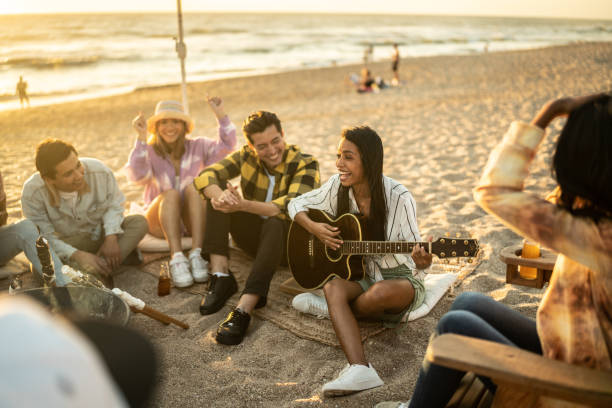 istock Friends having a picnic at the beach and playing guitar 1442723793