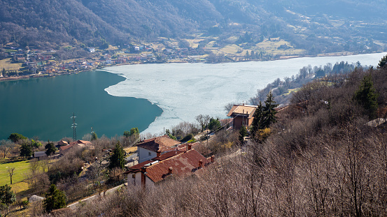Lake Endine, Bergamo, Italy. Aerial view of the lake in winter time. Partially frozen lake. Ice covering part of the lake. View from the hill