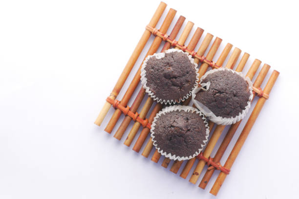 A home baker delicately applies chocolate icing to freshly baked cupcakes in a cozy kitchen environment. The scene highlights the joy and artistry of home baking.