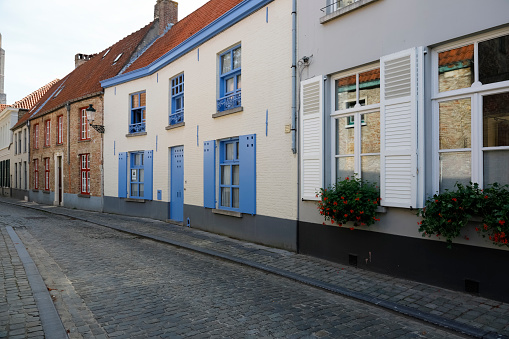 Bruges, Belgium - September 12, 2022: On a narrow street there are brick houses next to each other. Their colorful shutters, doors and window frames make up the picturesque landscape of the city