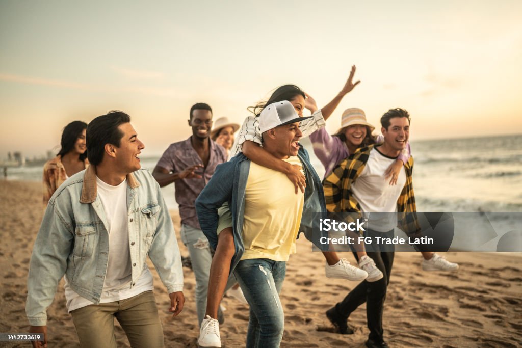 Friends walking and playing on the beach 20-29 Years Stock Photo