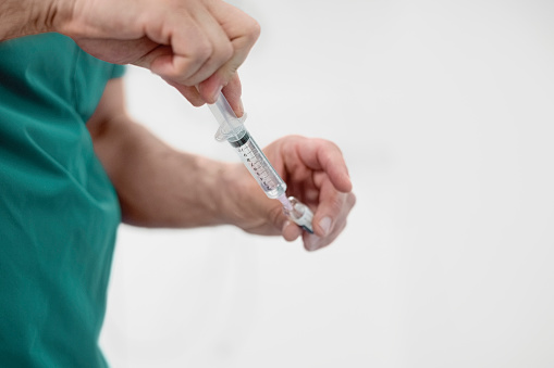 Close-up of a healthcare professional hand filling injection in syringe. Doctor is preparing medical injection in hospital.